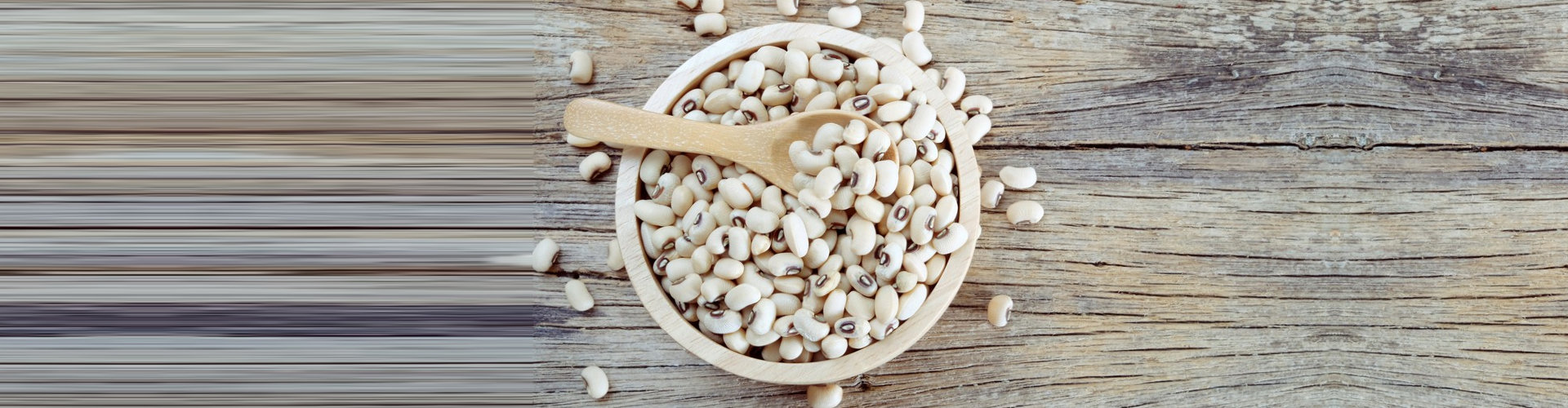 white beans in wooden spoon and bowl on a wooden table"
